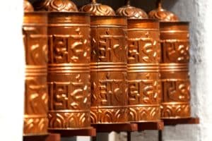 Buddhism Metal Prayer Wheels at Nepal Buddhism temple. According to the Tibetan Buddhist tradition, spinning such a wheel will have much the same meritorious effect as orally reciting the prayers. A tourist attraction in cultural Nepal tours and travels.