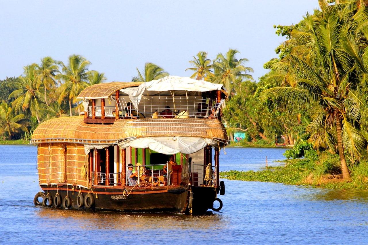 Under the coconut trees, a rice houseboat in the Kerala water canal